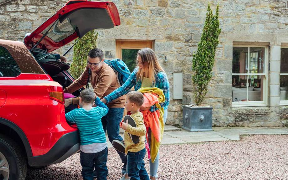 Family packing car to go on holiday outside their 